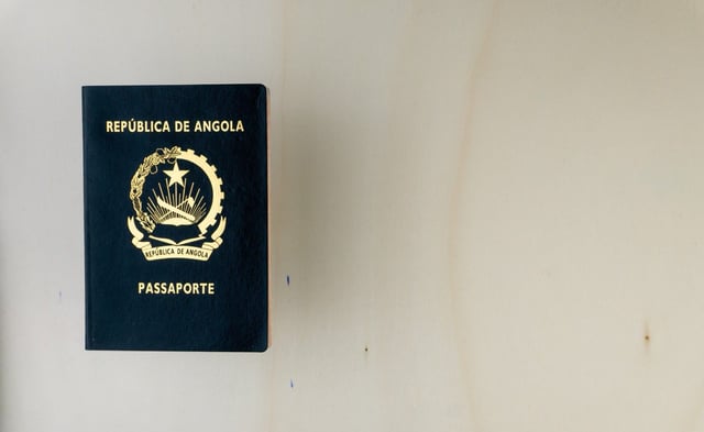 Angolan Passport Isolated On Wooden Table